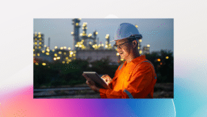 An engineer wearing a hardhat uses a digital tablet while working the night shift at petroleum oil refinery.