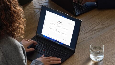 A person at a table with a drinking glass on the right side, working with Copilot.