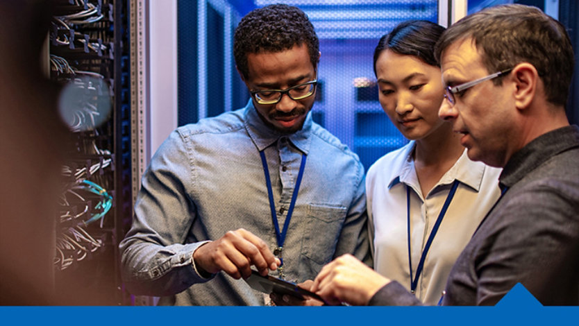 Three people looking at a single tablet device next to an open server device.