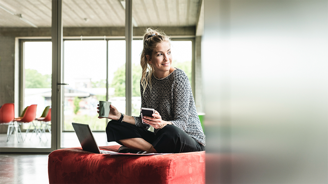 A businesswoman in a modern office, sitting on stool, using tools for task management