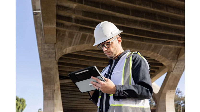 A person in a construction hat and vest using a Surface device