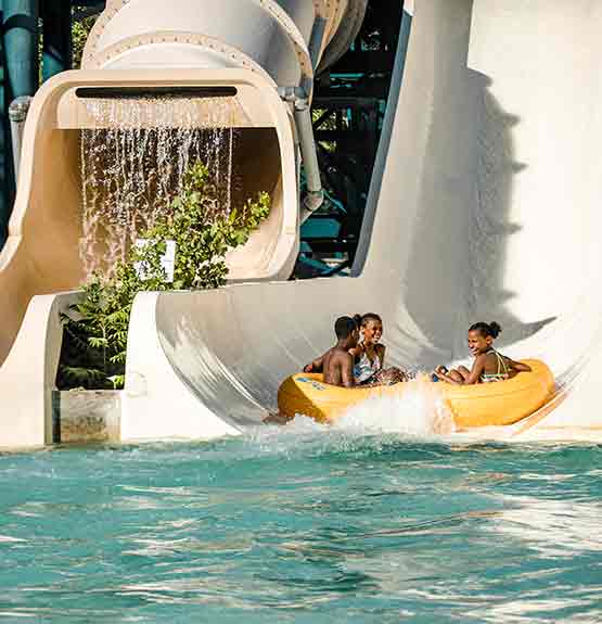 Enfants dans tube jaune dans glissade blanche avec bassin et seconde glissade avec chute d'eau