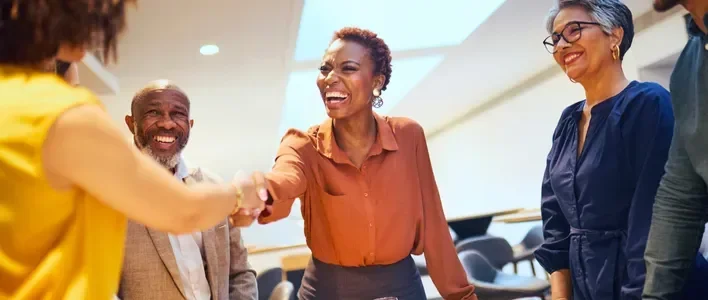 A group of four Five9 partners engaging in a welcoming handshake indoors.