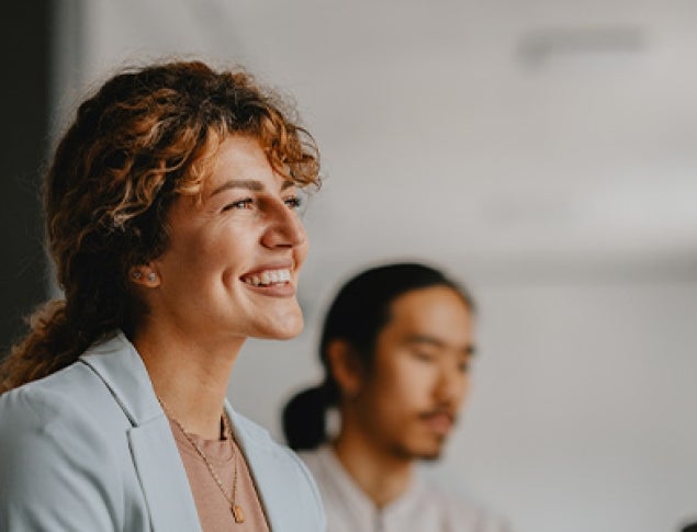 People in a meeting, smiling, engaged in conversation, with a bright, modern setting.